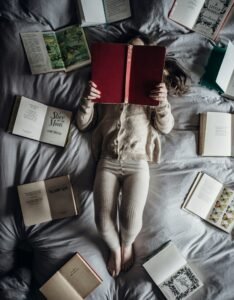 a little girl laying on a bed with lots of books